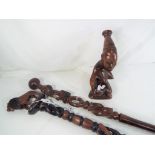 A wooden carved tribal figurine depicting a female and two highly carved African walking sticks (3)