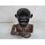 An original aluminium novelty money bank in the form of a black man, approximately 13 cm (h).