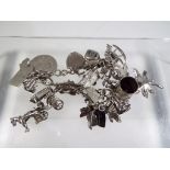 A white metal charm bracelet with a quantity of silver and white metal charms,