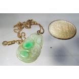 A jade carved pendant on a yellow metal chain and a silver brooch (unmarked) with carved mother of