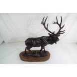 A cast, bronzed stag on a wooden plinth, approximately 48 cm (h).