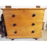A hinge-lidded pine linen chest with three faux drawers to the front and black bun handles,