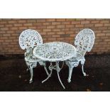 A wrought iron garden table with matching chairs.