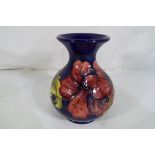Moorcroft Pottery - a medium sized Moorcroft Pottery bulbous vase decorated with hibiscus on a blue