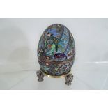 A Russian silver gilt and cloisonné enamelled egg, on three cast legs,