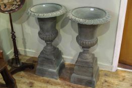 Pair cast campana style garden urns on stepped plinth bases,