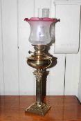 Victorian brass corinthian column oil lamp with ruby tinted etched glass shade