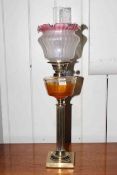 Victorian brass column oil lamp with clear glass reservoir and ruby tinted shade