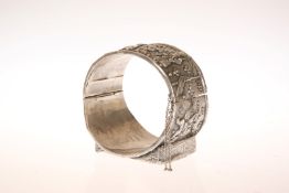 A CHINESE SILVER BANGLE, late 19th or early 20th Century, chased with figures and flowerheads,