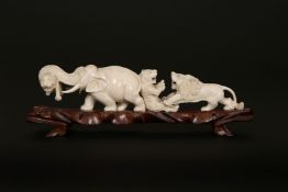A JAPANESE IVORY OKIMONO, MEIJI PERIOD, carved as lions and an elephant, on a wooden stand.