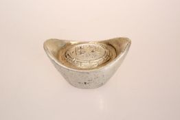 A CHINESE WHITE METAL TOKEN, of boat form, cast with calligraphy within a Greek Key border. 6.