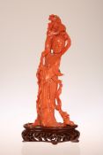 A CHINESE CARVED RED CORAL FIGURE OF A YOUNG WOMAN, or female deity, her right arm upraised,