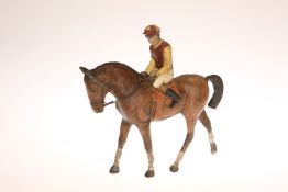 A COLD PAINTED BRONZE FIGURE OF A RACEHORSE WITH JOCKEY, in red and yellow silks, astride,