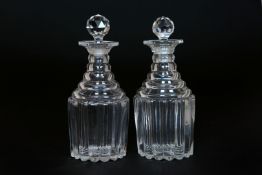A PAIR OF GEORGIAN GLASS DECANTERS, with terraced necks and reeded bodies, facet cut stoppers.