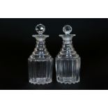 A PAIR OF GEORGIAN GLASS DECANTERS, with terraced necks and reeded bodies, facet cut stoppers.