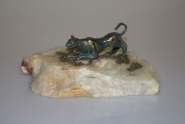 A GREEN PATINATED BRONZE MODEL OF A CHEETAH, stalking, on a naturalistic alabaster base,