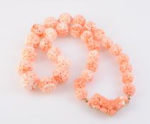 A CORAL NECKLACE, formed of thirty-one graduating carved coral beads,