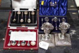 Pair of ornate silver dwarf candlesticks and three cased sets of silver teaspoons,