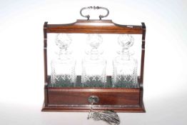 Mahogany three bottle tantalus fitted with three matching cut glass bottles