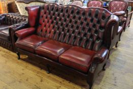 Wing-back settee with ox blood leather deep buttoned upholstery