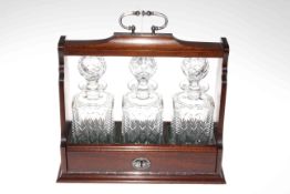 Mahogany three bottle tantalus fitted with three matching cut glass decanters