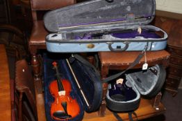 Three cased violins and bows
