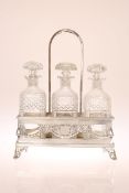 AN EDWARDIAN SILVER-PLATED THREE-BOTTLE DECANTER STAND,