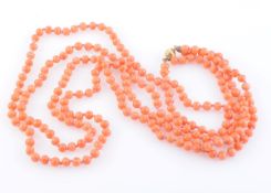 A CORAL BEAD NECKLACE, of uniform polished coral beads each strung knotted into two graduating rows,