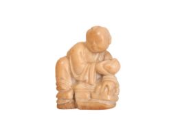 A CHINESE CARVING OF A CROUCHING YOUNG BUDDHA, holding a large pod. Height 6.