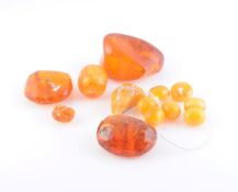 A COLLECTION OF AMBER COLOURED STONES, to include large unpolished amber and polished amber beads.