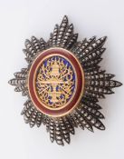 AN ENAMEL AND WHITE METAL BREAST BADGE, of radiating design.