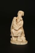 A JAPANESE IVORY OKIMONO, MEIJI PERIOD, carved as a teacher holding a scroll with raised fish,