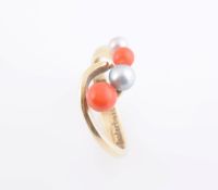 A CORAL AND SEED PEARL RING, the unusual crossover style mount set with two graduating coral beads,