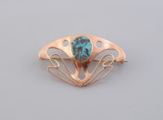 A GOLD AND TURQUOISE BROOCH, the stylised shield shaped mount with symmetrical cut-out detailing,