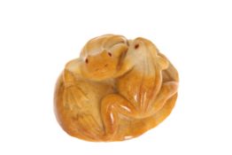 A CHINESE JADE CARVING OF TWO FROGS, modelled entwined on a stone, with red cabochon eyes,