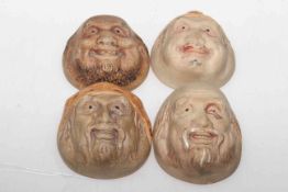 Set of four small Oriental pottery masks of smiling male figures, probably early 20th century,