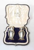 Cased pair of silver pepperettes,