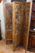 Oriental carved four fold vanity screen, the panels decorated in relief in figures,