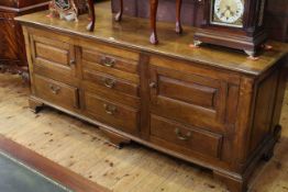 Antique oak dresser having three central drawers flanked by cupboard and drawers on shaped bracket