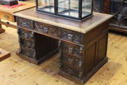 Heavily carved oak twin pedestal desk with lion mask handles and leather inset top