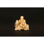 A JAPANESE IVORY NETSUKE, PROBABLY LATE 18th/EARLY 19th CENTURY, of a bearded sage seated on a deer.