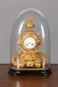 A FRENCH GILT-METAL MANTEL CLOCK, 19TH CENTURY, under a glass dome,