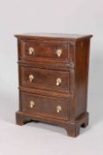 A SMALL OAK CHEST OF DRAWERS, fitted with three drawers with brass pulls, raised on bracket feet.