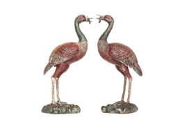 A PAIR OF PAINTED AND CAST METAL MODELS OF CRANES, each modelled standing on a naturalistic base.