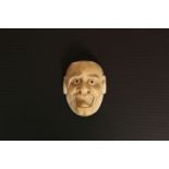 A JAPANESE IVORY MASK NETSUKE, MEIJI PERIOD, of a man with staring eyes and gaping mouth.
