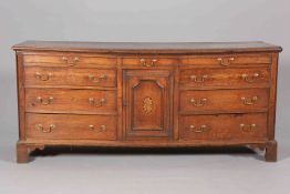 A GEORGE III OAK DRESSER BASE, fitted with an arrangement of drawers and an inlaid cupboard door,