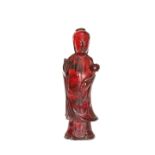 A CHINESE FIGURE OF GUANYIN, OF RED AMBER COLOUR, modelled standing,