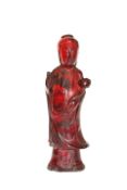 A CHINESE FIGURE OF GUANYIN, OF RED AMBER COLOUR, modelled standing,