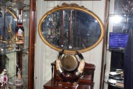 Oval gilt framed bevelled wall mirror and horn table gong and beater (2)