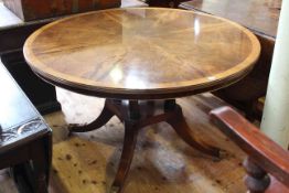Flame mahogany circular centre table raised on turned supports to four scrolled legs,